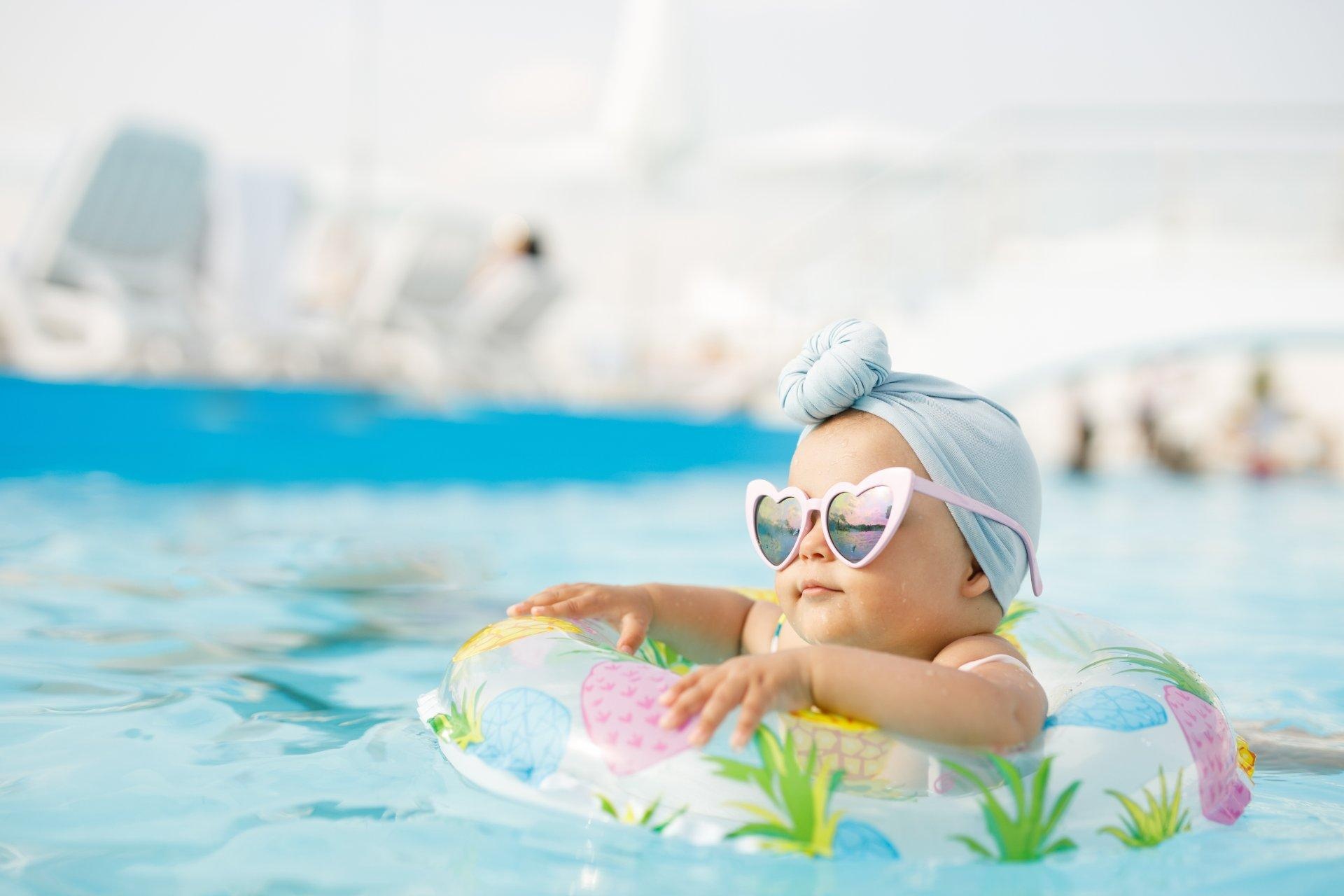 bebé con flotador y gafas de sol en piscina de hotel en el caribe