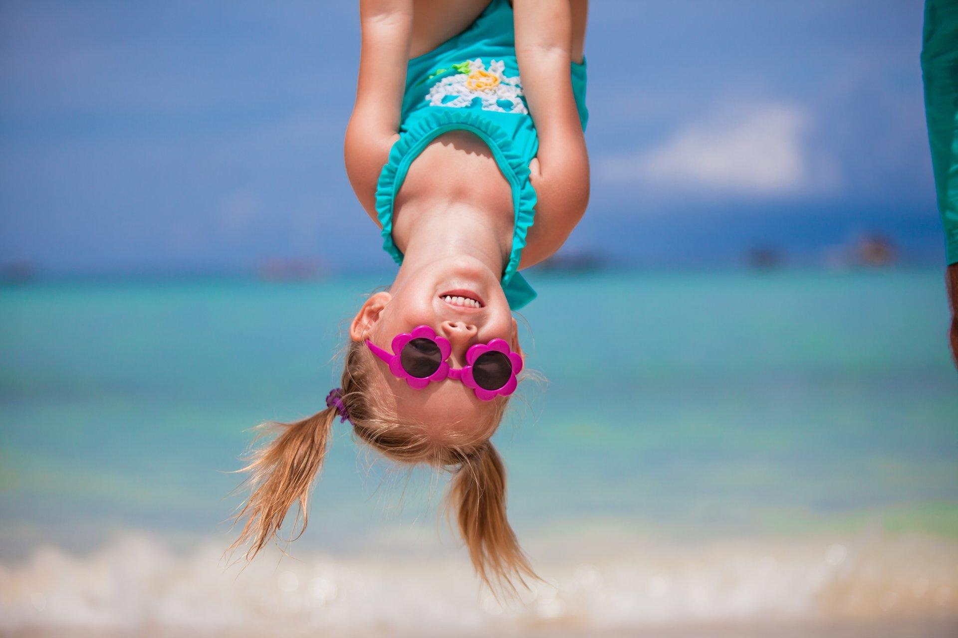niña con gafas de sol y bañador jugando en playa del Caribe