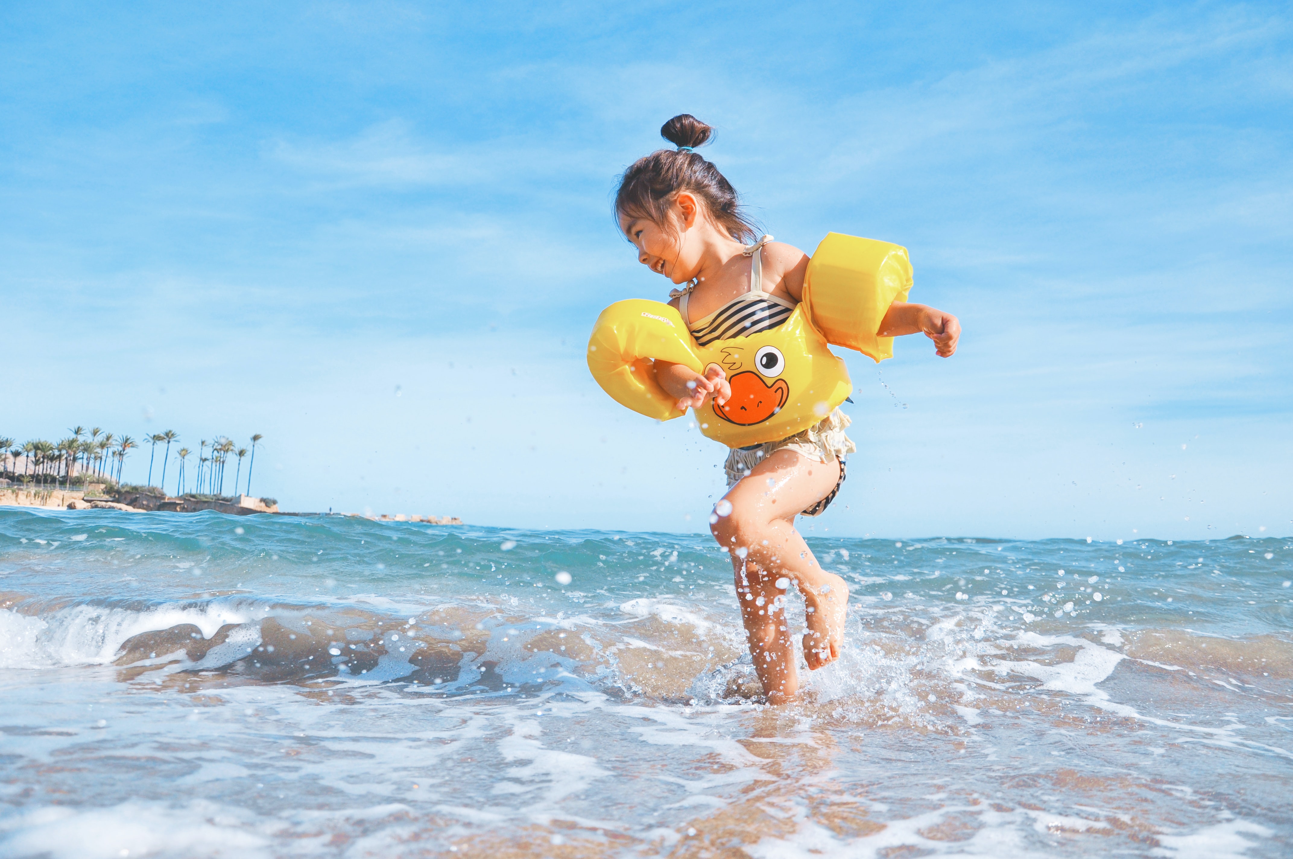 niña con flotador jugando en la orilla de la playa