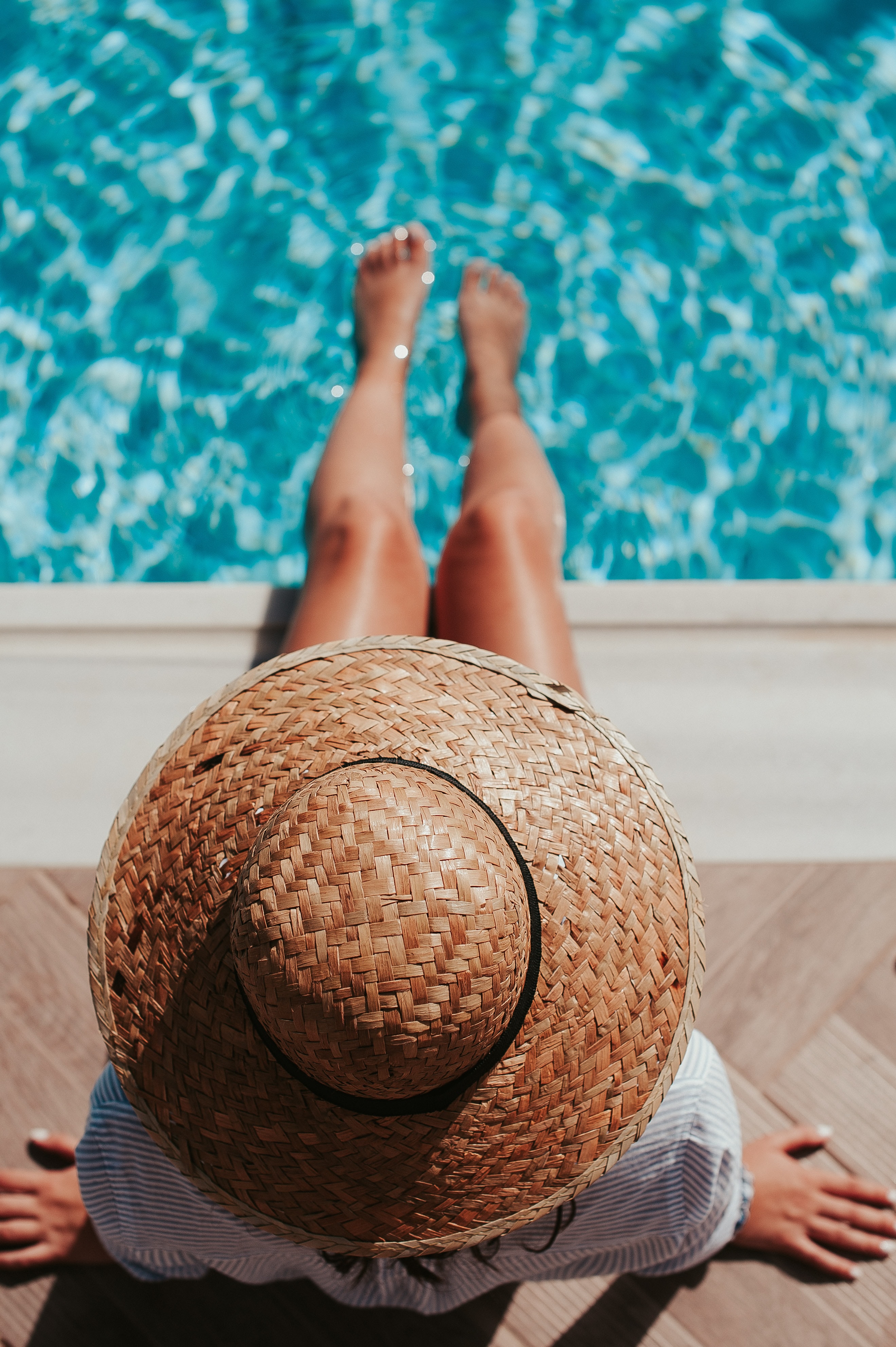 mujer con sombrero junto a piscina de hotel de lujo